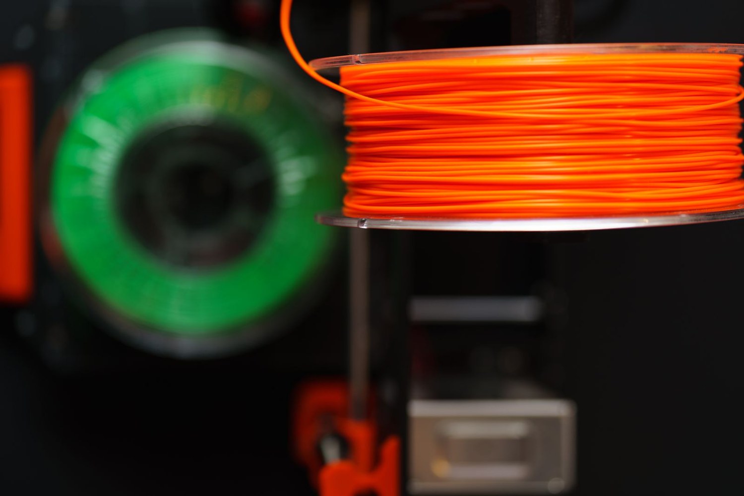 Orange and green filament spools on a printer