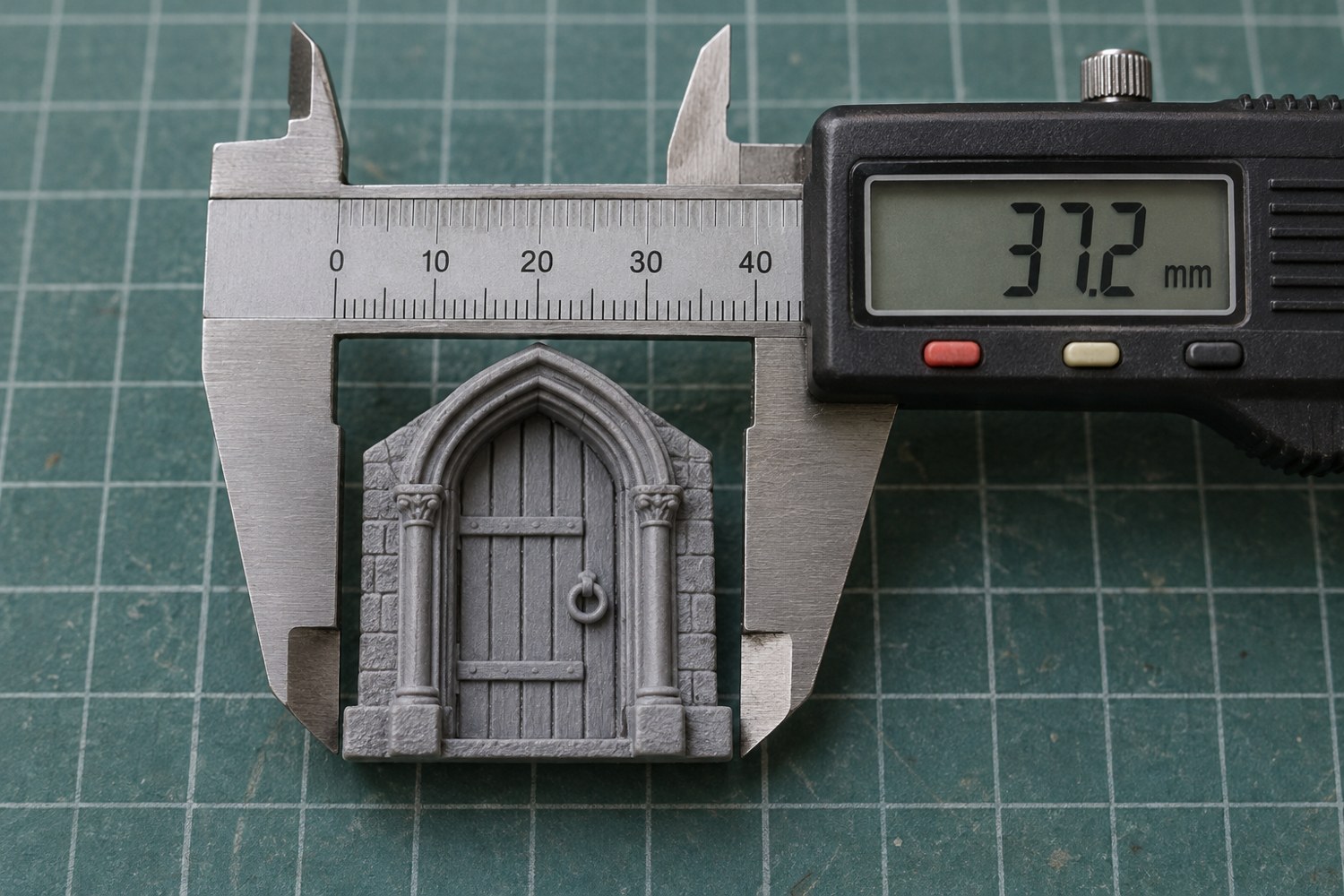 Illustration: Macro view of a metal digital caliper measuring the outer width of a small grey miniature doorway, clean jaws contacting opposite edges, neutral cutting mat