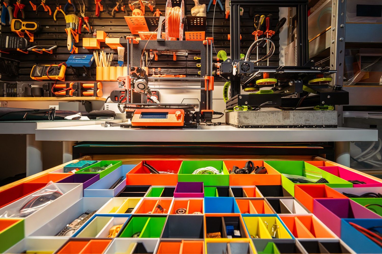Separate colourful parts bins beside a 3D printer